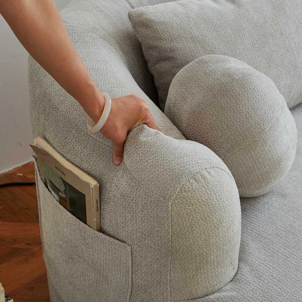 Hand pressing armrest of grey sofa showing side storage pocket