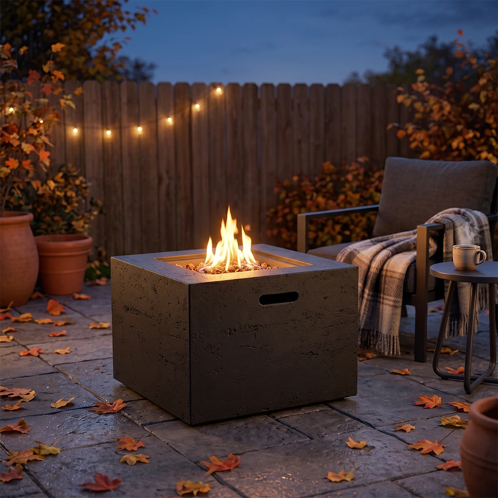Outdoor square gas fire pit burning on backyard stone patio in fall