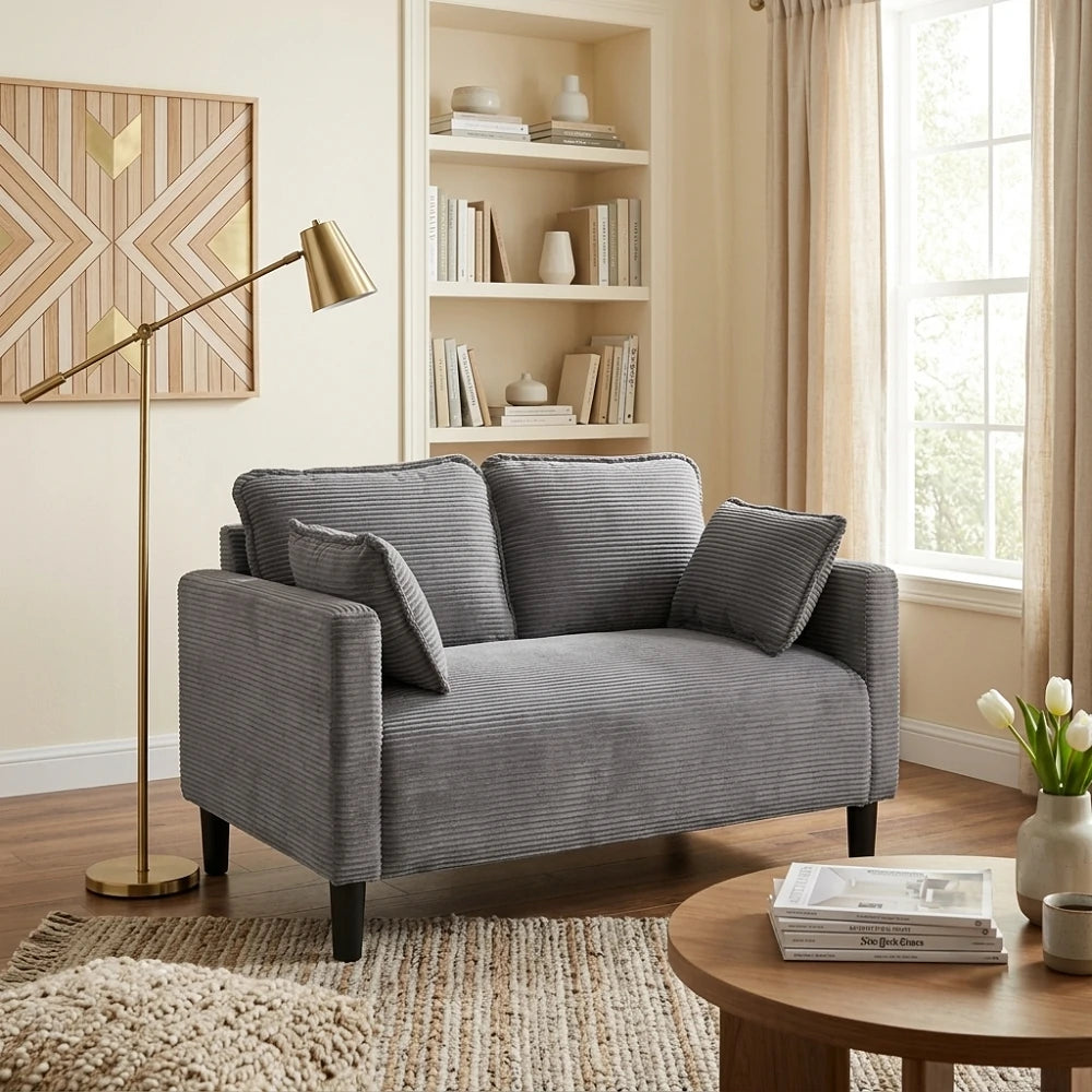 Side angle of grey corduroy sofa next to floor lamp