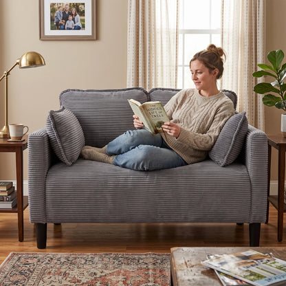 Woman lounging on comfortable grey corduroy loveseat